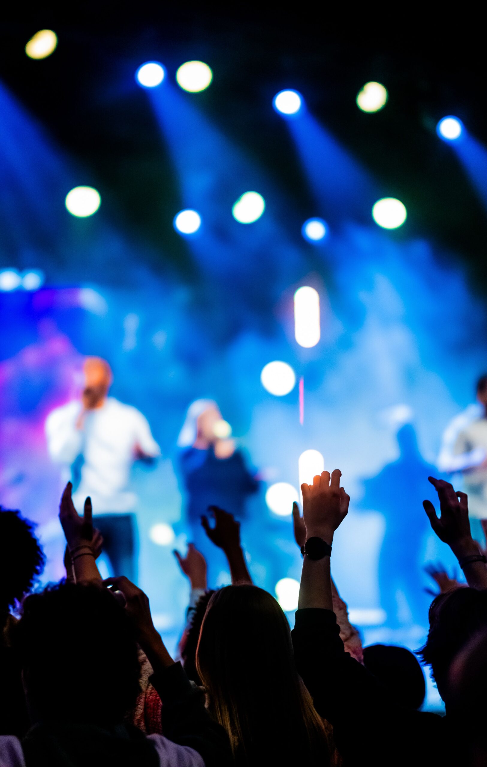 Vibrant concert scene with enthusiastic crowd enjoying live music under colorful stage lights.